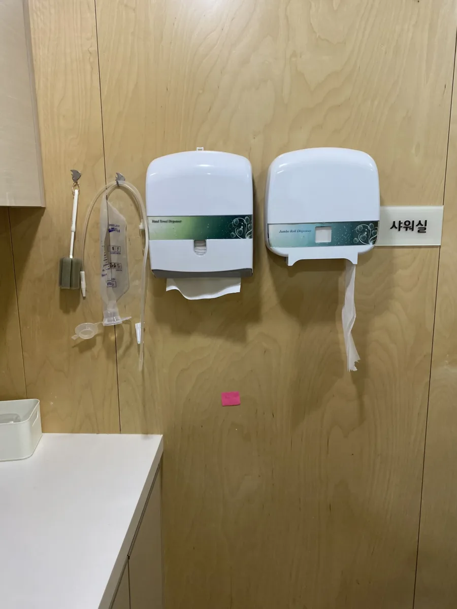요양시설 샤워실 나무 합판 벽면에 손잡이가 없는 모습 시공 전 단계